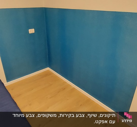 קיר צבוע חצי כחול וחצי לבן עם שקע חשמל